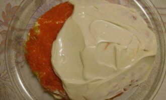 Următorul strat de salată este orezul cu sos de soia. Se întinde peste somonul roz cu o lingură, apoi se aromatizează cu maioneză. Întindeți ceapa, morcovii și ungeți generos stratul de morcovi și părțile laterale ale salatei cu maioneză.
