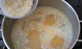 Skölj riset väl under rinnande vatten tills det är genomskinligt och tillsätt det i pannan med buljongen och grönsakerna. Tillsätt sedan lite mer salt, mald svartpeppar och blanda allt. Koka soppan i ca 20 minuter tills riset och potatisen är klara. 