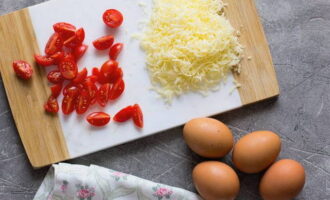 Com cuinar una truita esponjosa amb formatge en una paella? Prepareu el farcit: ratlleu el formatge amb un ratllador fi o de formatge, i talleu els tomàquets rentats i secs a meitats o quarts.