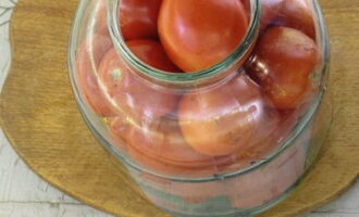 We plaatsen de tomaten losjes in de pot: we proberen kleinere vruchten op grotere te plaatsen. Schud de container zodat de tomaten stevig op elkaar passen.