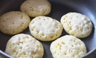 Na 10 minuten kun je beginnen met het bakken van de pannenkoeken. Zet de koekenpan op het vuur, verwarm hem en vet hem in met olie. Leg het deeg uit en bak de pannenkoeken 2-3 minuten aan één kant.