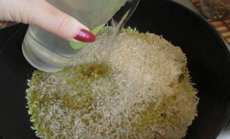Sarați orezul după gust și amestecați.Păstrați orezul și condimentele pe aragaz pentru câteva minute, astfel încât cerealele să absoarbă toate aromele. Se toarnă 200 de mililitri de apă.