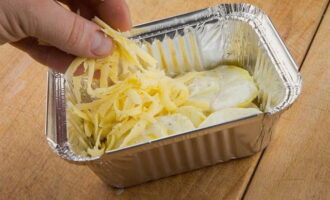 Unteu una safata de forn amb oli vegetal i poseu capes de patates i formatge, alternant-les. Aboqui nata per sobre de tot.