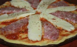 Așezați baza pe o farfurie potrivită pentru cuptorul cu microunde. Ungeți aluatul cu sos, acoperiți cu mozzarella și cârnați și stropiți cu ierburi italiene.