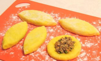 Espolvorear la superfície de treball amb farina. Traieu la massa de patates amb una cullera, feu-ne una bola i pasteu-la en un pastís pla. Col·loqueu el farcit al centre i tanqueu les vores. Arrebossat en farina. Espolvorear la superfície de treball amb farina. Traieu la massa de patates amb una cullera, feu-ne una bola i pasteu-la en un pastís pla. Col·loqueu el farcit al centre i tanqueu les vores.Arrebossat en farina.
