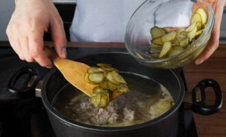 Vi lägger pärlkorn och pickles här. Salta och peppra efter smak och koka i ytterligare 20 minuter på låg värme. Stäng av spisen och låt soppan stå övertäckt på den avstängda spisen.