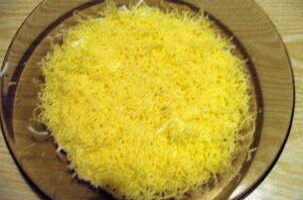 Grate ang keso sa isang pinong o katamtamang kudkuran, iwiwisik ito sa salad, at pahiran din ang layer na ito ng mayonesa.