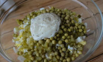 Voeg vervolgens groene erwten uit blik toe aan de salade, voeg mayonaise naar smaak toe, voeg zout en gemalen zwarte peper toe.