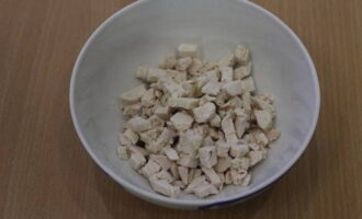 Cum să faci o salată cu pui, ananas și nuci? Pieptul de pui fiert se taie cubulețe mici și se pune într-un bol de salată.