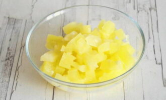 Despuiți borcanul cu ananas și turnați sucul într-o cană. Nu ar trebui să-l turnați, deoarece este foarte dulce și gustos. Pentru a scăpa ananasul de excesul de lichid, așezați-i pe prosoape de hârtie, apoi transferați-i cu grijă pe o masă de tăiat și tăiați-i cubulețe.