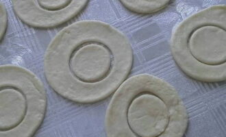 Ngayon ay kumuha ng amag o isang baso - isang lalagyan na may mas maliit na diameter - at gupitin ang mga butas sa gitna ng mga bilog. Ang resulta ay dapat na mga singsing. Iniwan namin ang kalahati ng mga blangko sa anyo ng mga buong bilog. 