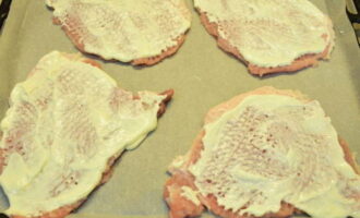 Bedek een bakplaat met perkament, leg het vlees erop en vet ze in met mayonaise.