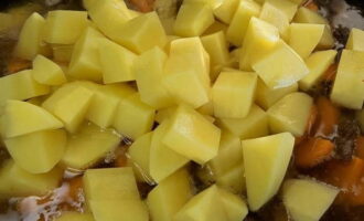 Tăiați cartofii curățați în cuburi mici și puneți-le într-un ceaun. Apoi adăugați suficientă apă fierbinte la aceste ingrediente pentru a acoperi complet carnea și legumele. Gatiti totul la foc mediu timp de 10 minute.