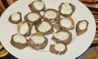 Leg de tongplakken op een platte schaal en giet de aromatische knoflook-zure roomsaus erover. 