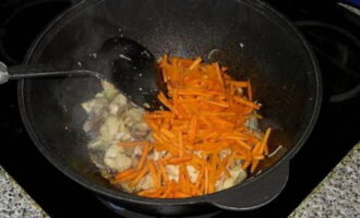 Voeg als de ui bruin is de wortels toe, voeg komijn en gemalen peper toe, roer en ga door met koken.
