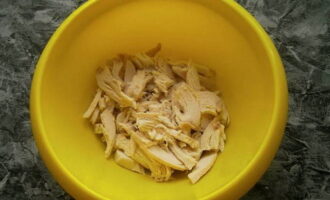 เราต้มเนื้อไก่ไว้ล่วงหน้า ปล่อยให้เย็น จากนั้นแยกออกเป็นเส้นใยแล้วส่งไปยังภาชนะที่เราจะคลุกสลัด