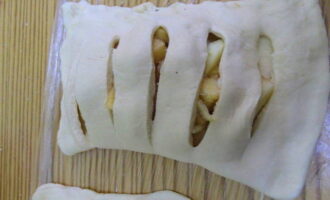 I-brush ang gilid sa gilid ng pagpuno ng tubig gamit ang isang pastry brush. Takpan ang pagpuno sa gilid na may mga puwang at kurutin ang mga gilid. Ginagawa namin ang parehong sa pangalawang layer ng kuwarta.