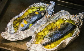 Ara connectem les vores del paper d'alumini per sobre, tanquem-les amb força i ho passem tot a una safata de forn. Poseu el peix i les patates al forn preescalfat a 180 °C durant mitja hora. Passat aquest temps, desenrotlleu el paper d'alumini i enforneu durant 15-20 minuts més fins que estigui fet.