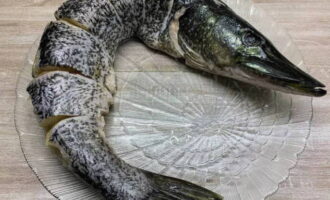 Vi tvättar fisken noggrant under vatten, tar bort fjäll, inälvor och fenor och gör djupa snitt var 5-7 centimeter.