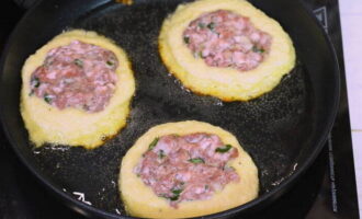 De îndată ce turțile s-au întărit puțin, puneți deasupra puțină umplutură de carne (aproximativ o lingură și jumătate). De îndată ce turțile s-au întărit puțin, puneți deasupra puțină umplutură de carne (aproximativ o lingură și jumătate).