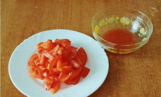 Snij de tomaten in plakjes en knijp ze lichtjes uit (giet het vrijgekomen sap in een kom).