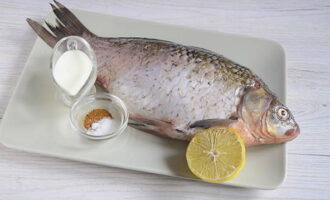 Hur bakar man läckert karp i ugnen? Vi förbereder produkterna enligt listan: vi tar bort fisken, skär av fenorna och gör ganska djupa snitt på båda sidor med en vass kniv.