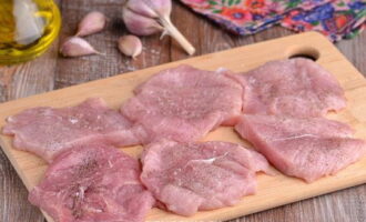 Kumuha ng matalim na kutsilyo at gupitin ang baboy. Dapat mayroong 6 na piraso. Kung ang mga hiwa ay masyadong makapal, kailangan nilang maingat na gupitin sa kalahati gamit ang isang kutsilyo. Upang gawin ito, gupitin ang bawat piraso sa gitna at ilipat ang kutsilyo sa gilid. Hindi namin ginagawa ang hiwa sa lahat ng paraan at buksan ang mga piraso. Budburan ang mga hiwa ng asin at paminta sa lahat ng panig.