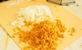 Amíg a hal pácol, kezdjük a zöldségekkel. Pár meghámozott hagymát apró kockákra vágunk. A sárgarépát durvára lereszeljük, a felső szennyezett rétegtől is megtisztítva.