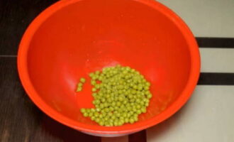 Obre una llauna de pèsols en conserva, escorre el líquid completament i aboca els pèsols en una amanida.