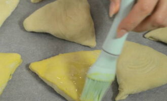 Passem els espais en blanc a una safata de forn, prèviament coberta amb una làmina de pergamí, amb la costura cap avall i untem amb el rovell batut i la llet.