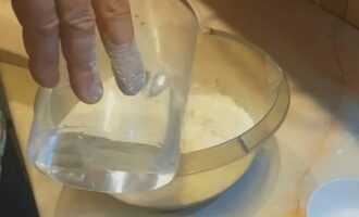 Vervolgens worden kokend water en zout in porties bij de bloem gegoten en tegelijkertijd wordt het deeg gekneed totdat al het kokende water is gebruikt.