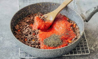 Maal de gepelde tomaten fijn met een blender op maximale snelheid en giet deze massa met het gehakt in een koekenpan. Bestrooi het gerecht vervolgens met zout, peper en kruiden (basilicum en oregano), meng en laat de Bolognese op laag vuur 20 minuten sudderen.