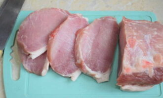 Paano maghurno ng mga pork chop na may keso at kamatis sa oven? Gupitin ang karne sa mga bahagi, mga isang sentimetro ang kapal. Ilagay ang mga piraso sa isang cutting board, takpan ng cling film (upang maiwasan ang mga splashes) at talunin sa magkabilang panig, pagkatapos magwiwisik ng asin at ang iyong mga paboritong pampalasa na sumasama sa baboy.