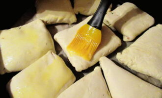 Folreu una safata de forn amb paper de forn i col·loqueu-hi el samsa, les costures cap avall. Pinteu bé la part superior amb ou per daurar els pastissos.