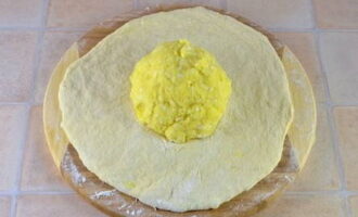 Cán thành phẩm đã chuẩn bị thành một chiếc bánh dẹt và đặt một viên khoai tây và phô mai vào giữa.