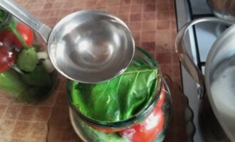 Những quả cà chua được phủ một lá cải ngựa. Sau đó, rau trong lọ được đổ với nước sôi, đậy nắp lại và để trong 10 phút.