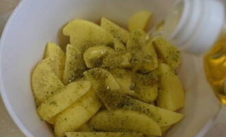 Apoi turnați ulei vegetal în cartofi și amestecați totul astfel încât feliile să fie acoperite uniform cu ulei.
