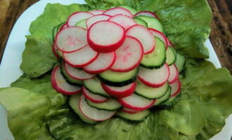A szeletelt retket és uborkát piramisba rakjuk, és a salátalevelekre rétegezzük.