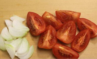 Els tomàquets i les cebes es preparen de manera molt senzilla per a l'hivern. Esbandiu els tomàquets seleccionats per a la preparació sota aigua corrent. A continuació, talleu-los a rodanxes grans, traient-ne les tiges. Peleu les cebes i talleu-les a mitges anelles.Esbandida els verds