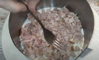 Upang mabuo ang salad, kumuha ng nababakas na culinary ring. Ang ibaba ay pinahiran ng mayonesa at ang mga cube ng pinausukang dibdib ng manok ay inilatag bilang unang layer.