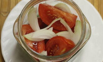 A continuació, col·loqueu compactament les rodanxes de tomàquet al pot, repartint la resta de la ceba entre elles. Agiteu el pot de verdures un parell de vegades perquè els trossos de verdures s'assentin més fort.
