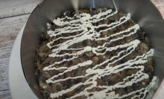 Ang ika-apat na layer ay inilatag na may mga champignon na pinirito ng mga sibuyas at tinatakpan ng isang mata ng mayonesa.