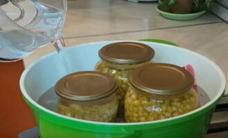 Tapeu els pots amb tapes i poseu-los en una cassola gran per esterilitzar, cobrint el fons amb una tovallola. Ompliu els pots amb aigua calenta fins al nivell dels penjadors i deixeu-ho bullir a foc mitjà.
