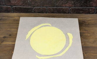 Gumamit ng magandang kalidad ng baking paper. Alisin ang isang tinapay mula sa refrigerator. Gamit ang isang rolling pin, igulong ang kuwarta sa kapal na hindi hihigit sa 2 milimetro. Gumamit ng takip o plato upang bigyan ang crust ng isang bilog na hugis. Iwanan ang mga scrap dito.