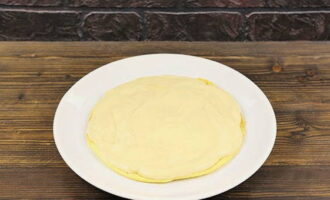 Maglagay ng isang kutsarang puno ng cream sa ulam kung saan mo ibubuo ang masarap na cake at ikalat ito. Ilagay ang puff pastry sa itaas at pindutin nang bahagya upang dumikit ito sa ibaba. Kumalat nang mapagbigay na may cream.
