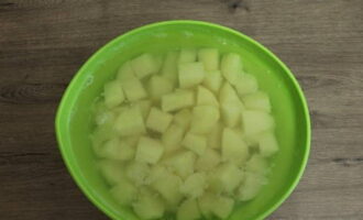 Was de aardappelen om het zand te verwijderen, verwijder de schil met een dunschiller of schil met een mes. Snijd in blokjes. Doe in een kom en bedek met koud water.