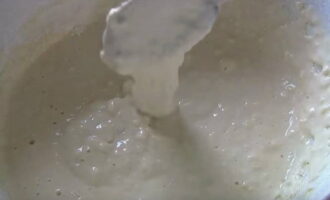 Cerneți făina de grâu într-o sită. Apoi turnați-l în porțiuni în baza de chefir, amestecând simultan ingredientele cu o lingură. Cerneți făina de grâu într-o sită. Apoi turnați-l în porțiuni în baza de chefir, amestecând simultan ingredientele cu o lingură.
