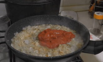 Afegiu 2 cullerades de pasta de tomàquet a la ceba fregida amb all, remeneu-ho i deixeu-ho coure a foc lent durant 5 minuts. Afegiu 2 cullerades de pasta de tomàquet a la ceba fregida amb all, remeneu-ho i deixeu-ho coure a foc lent durant 5 minuts.