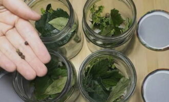 Rentar els pots per a la preparació amb refresc i esterilitzar de qualsevol manera. Bullir les tapes. Rentar les fulles verdes. Col·loqueu espècies a cada pot segons les proporcions de la recepta.