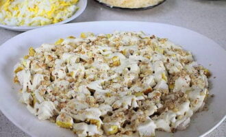 Ang lahat ng mga sangkap ay handa na. Maaari mong simulan ang pag-assemble ni Tiffany. Ilagay ang mga piraso ng manok sa pantay na layer sa isang serving salad bowl at takpan ng manipis na mesh ng mayonnaise dressing. Budburan ang ikatlong bahagi ng tinadtad na mani sa ibabaw nito.